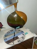 Front view of wall clock and wooden vase together