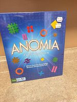 Front of sealed Anomia Party Edition box showing title and graphics