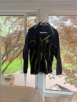 Front view of black Antigua fleece pullover with neon chartreuse accents hanging on hanger
