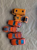 Six orange diecast vehicles laid out