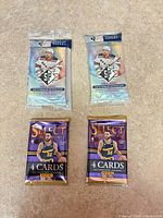 Two Upper Deck SP 2020-21 hockey packs and two Panini Select 2022-23 NBA packs on table surface