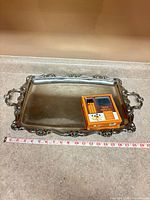 Top view of silver tray with box on surface and tape measure
