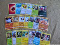 Assortment of Pokémon TCG cards laid out, shows variety of types and trainers