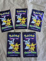 Five sealed Pokémon Trick or Trade booster packs laid out front side up