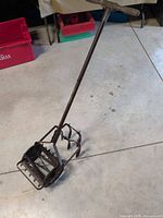 Full view of hand cultivator showing wood T-handle, steel shaft, rotary head