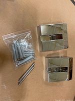 installation hardware bag, wall anchors and screws beside square chrome mounts