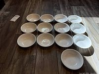 Thirteen white bowls arranged rim-up showing interiors