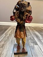 Full view of paper mache male figurine on wood base