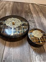 Large and small lidded boxes showing gold tree design