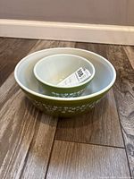 Two nested Pyrex green floral bowls showing relative sizes and exterior pattern