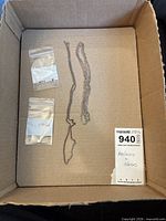 Box containing two silver necklaces and two bags of loose stones