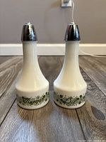 Front view of both milk glass cruets with chrome tops