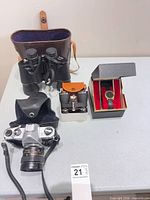 Overall shot showing camera, binoculars, opera glasses box, wristwatch in box