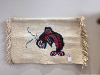 Full view of rug on wall showing fish motif and fringe