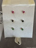 Three pairs gemstone stud earrings on display