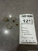 Group shot of three rings and one pendant on surface with weight note visible