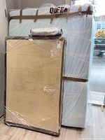 Shrink-wrapped adjustable platform foundation leaning against wall