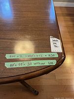 Top corner of table with tape showing dimensions and finish wear