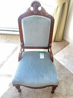 Front view of carved wood chair with blue velvet upholstery