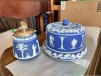 Biscuit jar and cake dome side by side showing blue jasperware with white relief