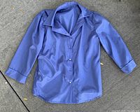 Full view of periwinkle blue silk blouse laid flat