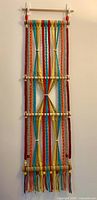 Full view of multicoloured macramé wall hanging on wall