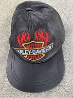 Front view of black leather cap showing embroidered flaming Harley-Davidson Motor Cycles logo