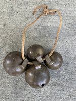 All four large spherical metal bells tied together with rope, showing size, shape and patina