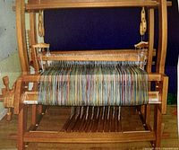 Front view of assembled Nilus Leclerc pine floor loom with warp threads and treadles visible