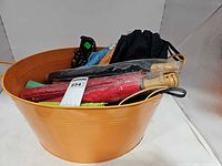 Top view of orange metal tub filled with assorted umbrellas showing variety of colors and handles