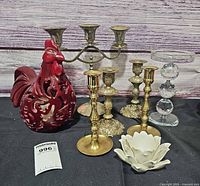 All items grouped: rooster luminary, brass candelabra, four brass candlesticks, glass candlestick, lotus holder
