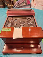 Open pink case showing cocktail shaker, jigger, stopper, opener, two coasters and wooden letter box in front