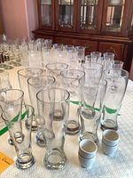 Group of tall Pilsner glasses with beer glasses and stacked egg cups on table