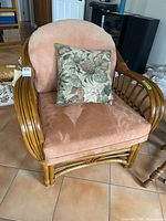 Front angle of rattan armchair with floral pillow