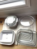 Group of white ceramic and clear glass casseroles showing overall lot