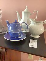 Group shot of coffee pot, cream pitcher, blue teapot, cup and saucer