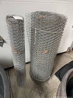 Two rolls of chicken wire standing upright showing size difference