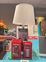 Full view of whisky tin lamp with shade flanked by telephone booth tins