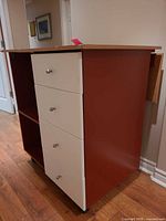 Front view showing four white drawers, open shelf, reddish-brown sides