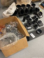 Overview of box with clamps, copper wire, and array of plastic dust collection fittings on floor