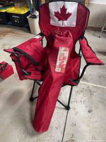 Open red camp chair with Canada flag backrest and second chair in carry bag