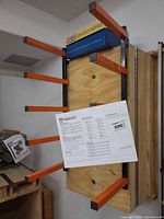 Rack mounted on wall showing orange folding arms and manual