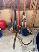 Group of shovels, axe, hand tiller, hose, hatchets, machete, loppers, rake, tamper and post hole digger