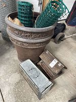 Planter with fencing rolls, burlap inside, live trap and bird feeder on floor