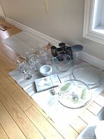 Group shot of all items on floor: dessert bowls, Irish coffee mugs, Pyrex measuring cup, tall container, cake plate, pie plate, marble slicer, bowl