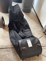 Full view of black rolling golf travel bag lying on floor