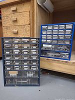 Two blue metal-frame hardware cabinets with resin drawers on workshop floor