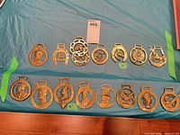 All sixteen brass harness ornaments displayed in two rows