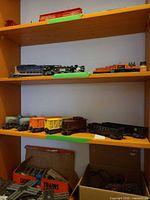 Shelf with multiple Lionel freight cars including Sunoco tanks, stock car, Baby Ruth boxcar, caboose and hoppers