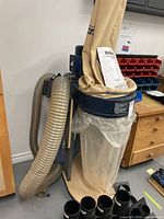 Full view of dust collector on wheeled plywood base with bags, hose and fittings visible
